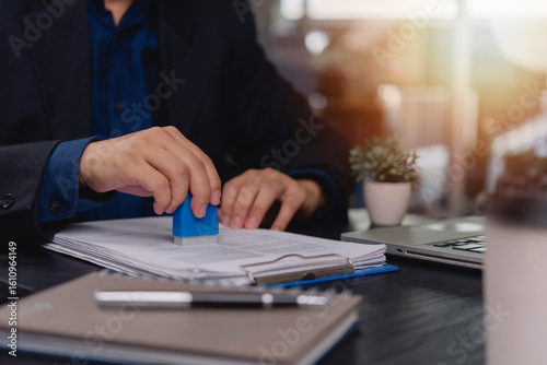 Billede på lærred Close-up shot of a hand using a rubber stamp to officially mark a document, showing signing, approval, or legal validation procedures in the workplace
