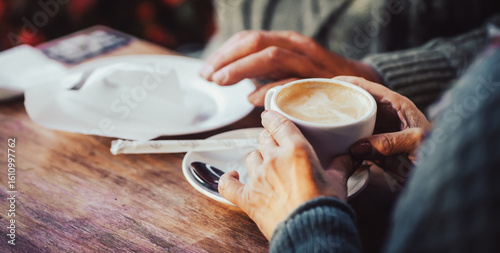 An elderly couple drinking morning coffee with croissants.