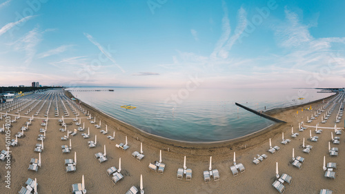 Fototapeta Naklejka Na Ścianę i Meble -  Lignano Pineta beach in Italy. Eempty sunbeds and calm sea during summer vacation.