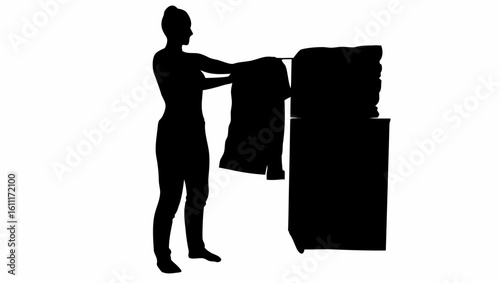 Silhouette of a woman with a towel on her head hanging a garment on a rack next to a cabinet stack