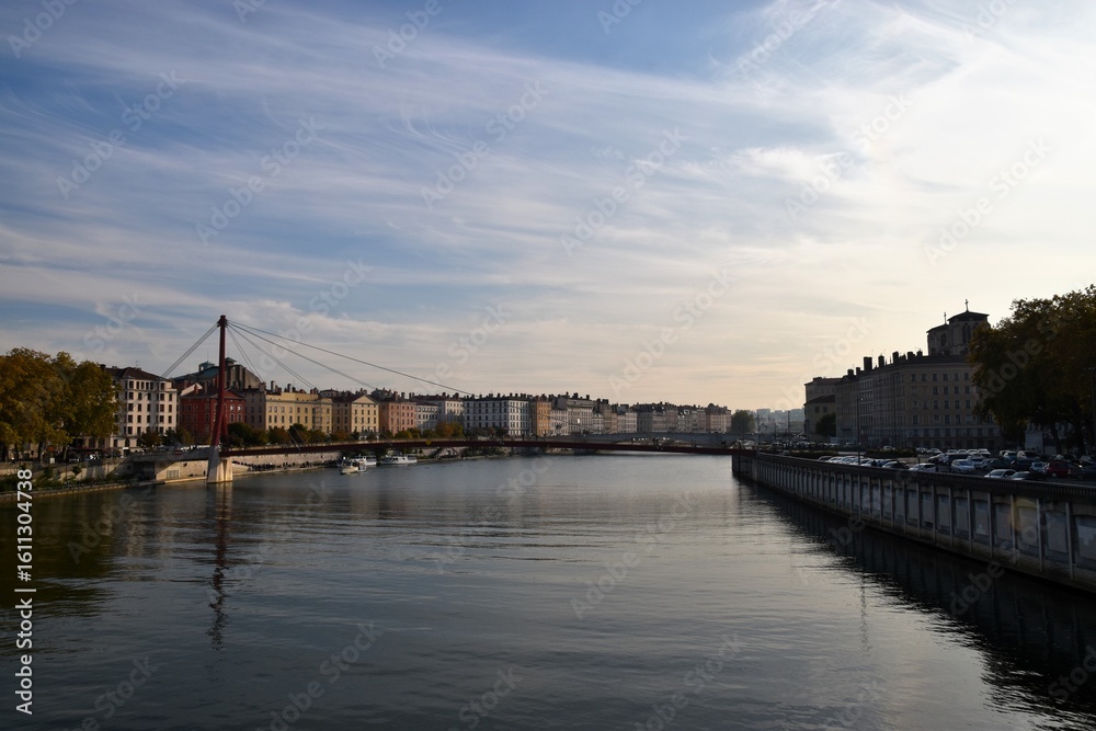 Naklejka premium Historic cityscape of Old Town (Vieux Lyon) and the Saône River at dusk, featuring the red Passerelle Saint-Georges footbridge in Lyon, France, a UNESCO World Heritage Site