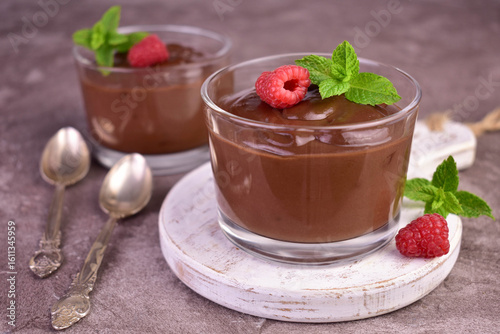Chocolate mousse with raspberries in glass cups on a gray background.
