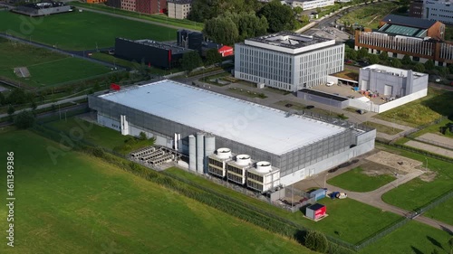 Aerial view of a modern data center with visible rooftop cooling systems in a green tech campus