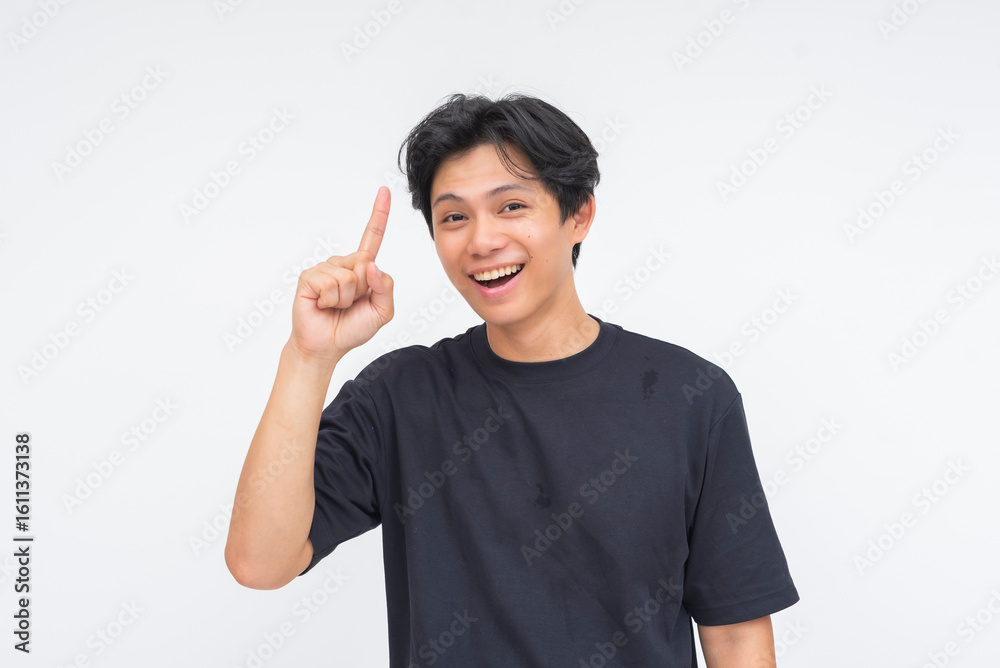 A happy young Asian man smiling with delight, confidently lifting one finger as if having a lightbulb moment. Isolated on a white background. A happy young Asian man smiling with delight, confidently lifting one finger as if having a lightbulb moment. Isolated on a white background.
