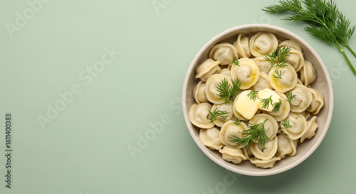 Dumplings with Butter and Dill in Bowl on Pastel Green Background