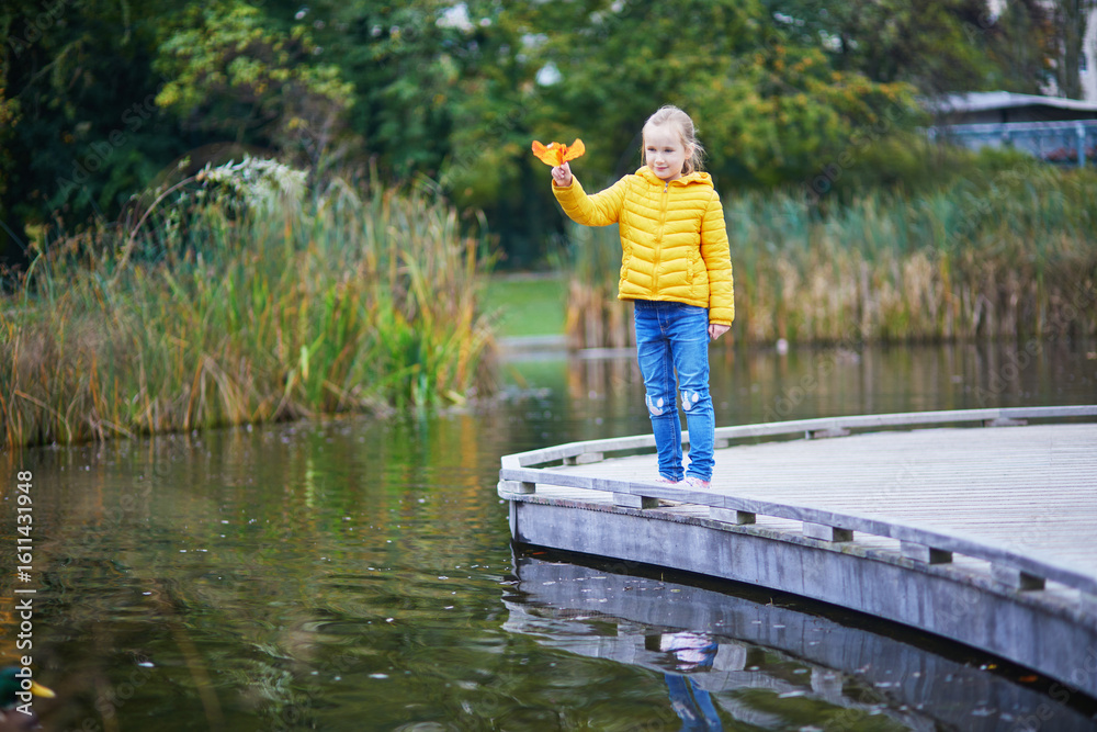 Fototapeta premium Cheerful little girl enjoying her walk in autumn park in Paris, France.