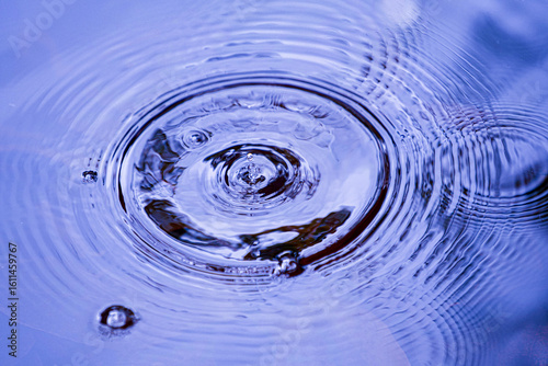 Fotografie Raindrops falling on smooth surface of water