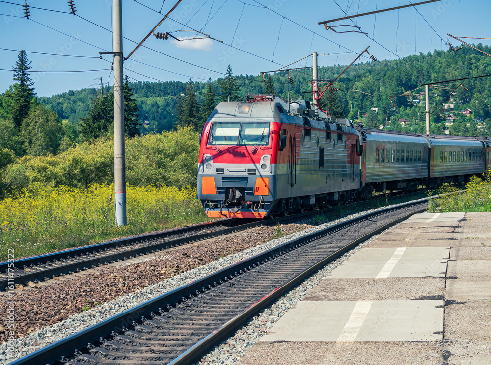 Naklejka premium Passenger train pulled by an electric locomotive on the Trans-Siberian Railway