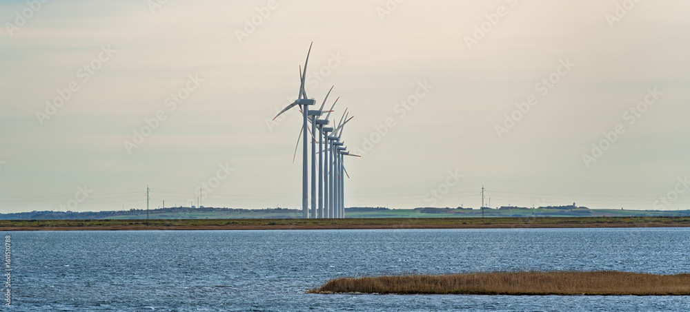 Fototapeta premium Wind Turbines Majestically Standing Tall Over the Serene and Peaceful Waters Nearby