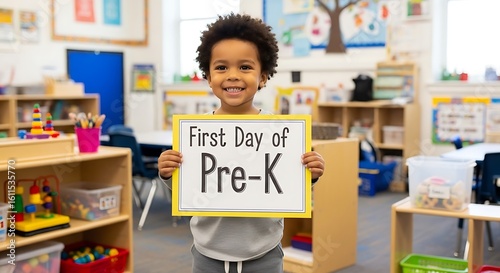 A smiling child holds a sign that says first day of pre k in a bright and colorful classroom setting