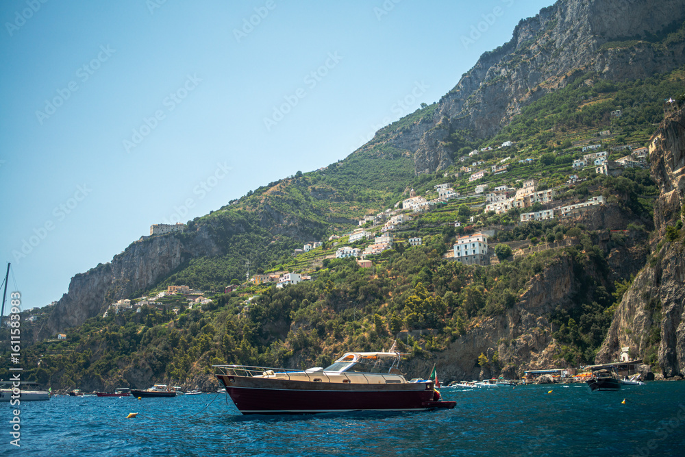 Obraz premium A breathtaking view of the Amalfi Coast showcasing dramatic cliffs, crystal-clear blue waters, and charming coastal architecture.