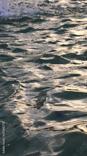 Abstract water surface background: vertical mobile video of water waves during sunset