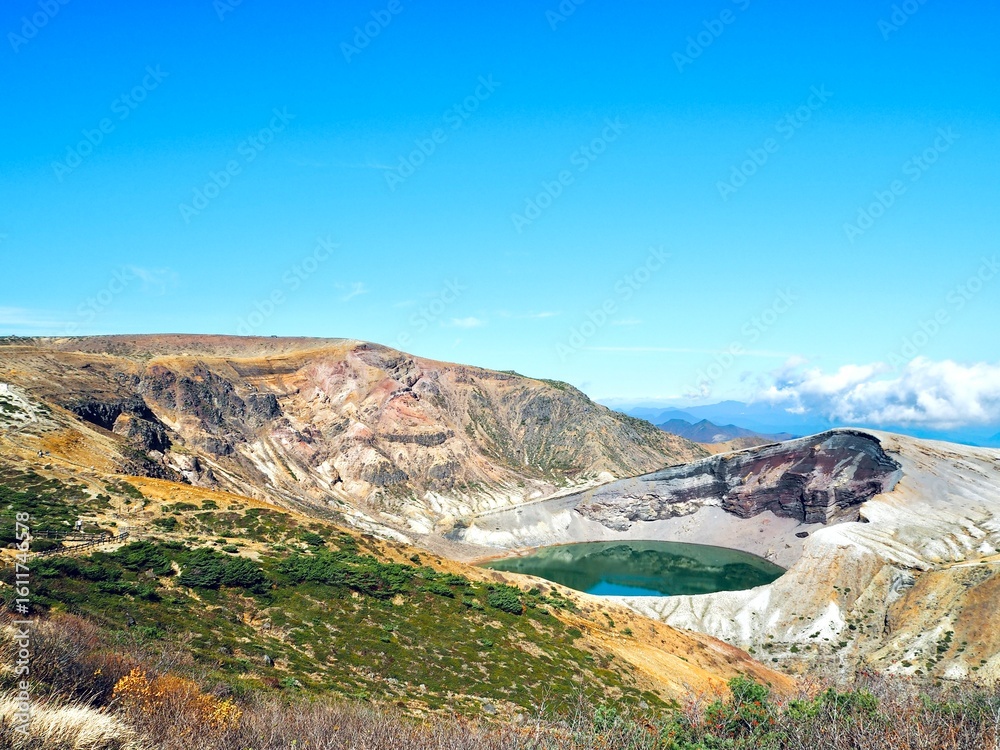 Fototapeta premium A breathtaking volcanic crater lake Okama on Mount Zao surrounded by rugged mountains.