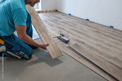 Wallpaper Mural Floating floor work. The worker hold the board of vinyl plank before insert to the floor click system. Torontodigital.ca
