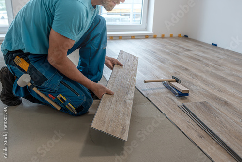 Wallpaper Mural Floating floor work. The worker hold the board of vinyl plank before insert to the floor click system. Torontodigital.ca