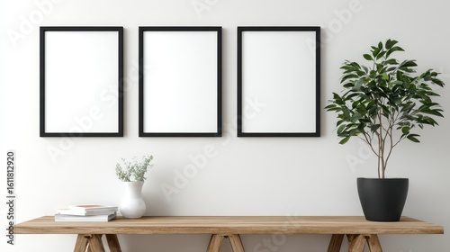a 4k photo of white wall with three black framed pictures and a potted plant 
