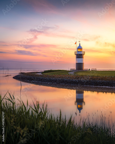 Sonnenuntergang an einem kleinen Leuchtturm an der deutschen Nordseeküste.