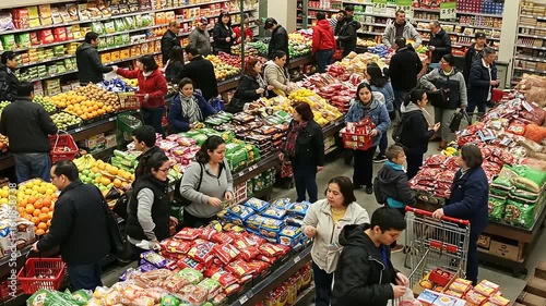 Busy grocery store scene with shoppers selecting fresh produce and packaged goods