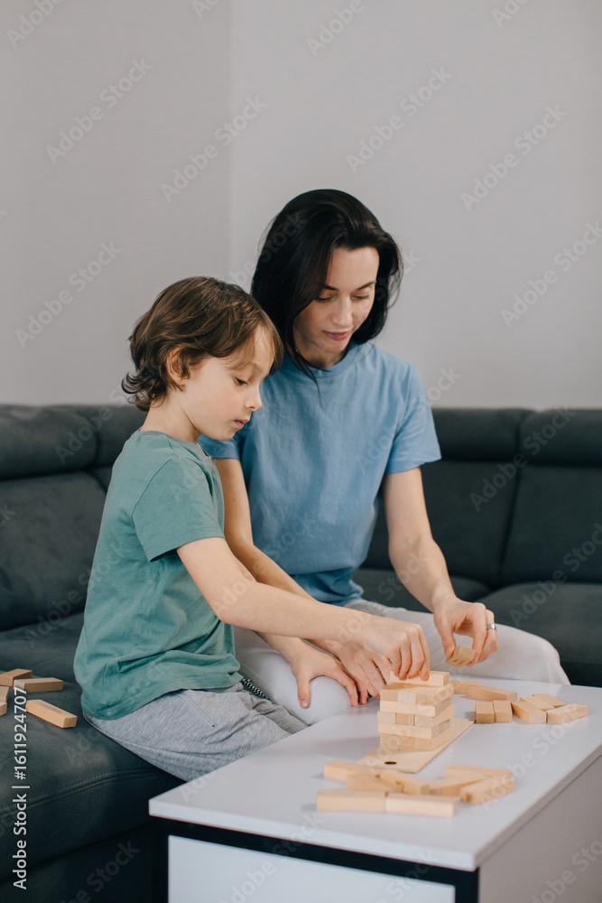 Fototapeta premium Mother and son building tower with wooden blocks at home