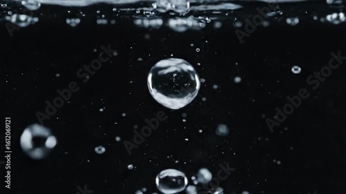 Close up macro shot of clear water bubbles rising and bursting in slow motion against a dark black, water, bubbles, rising, bursting, macro, close up, slow motion, liquid, underwater, dark background,