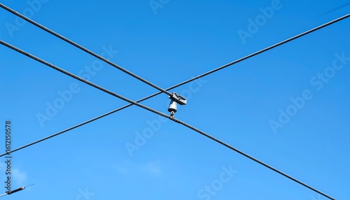 Overhead trolley wires intersect against a clear blue sky