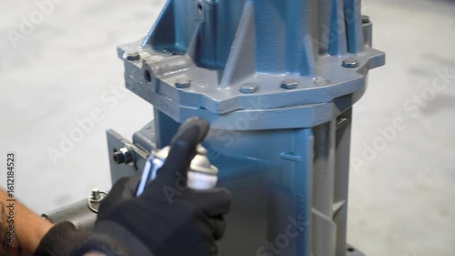 Mechanic applying spray paint on industrial part
