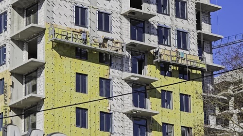 Construction workers installing thermal insulation on building facade