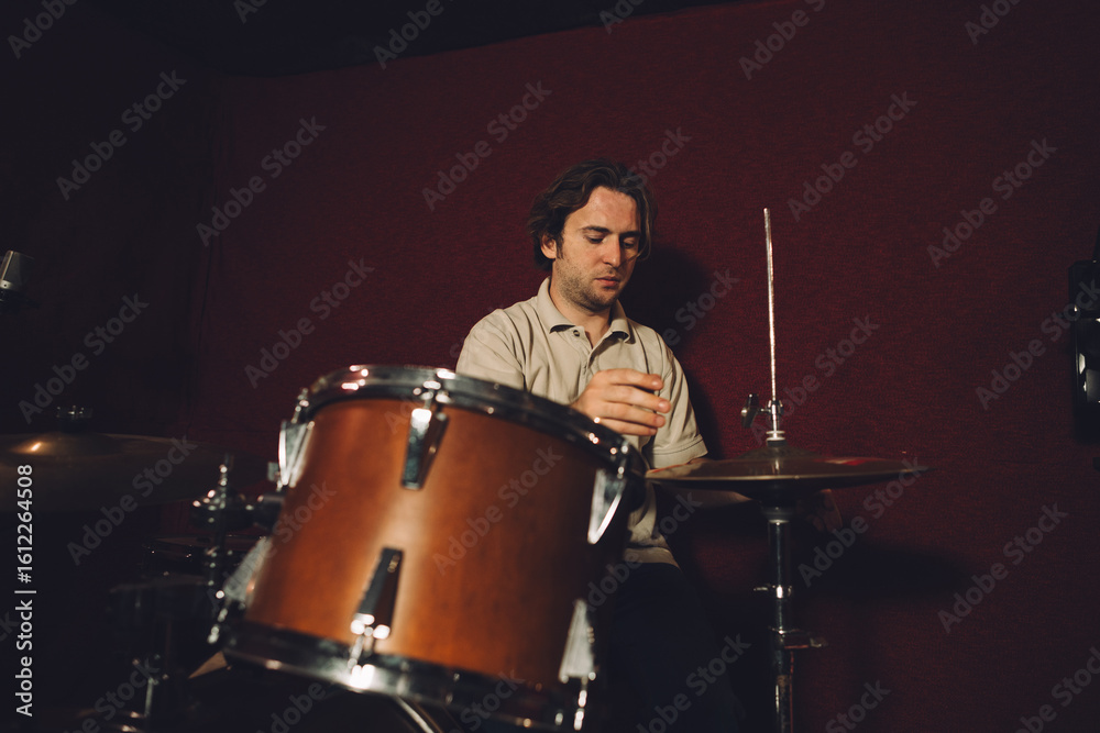 Fototapeta premium Drummer playing drums in recording studio with red background