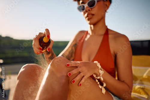 Canvas Print Close up of black woman applying suntan lotion.