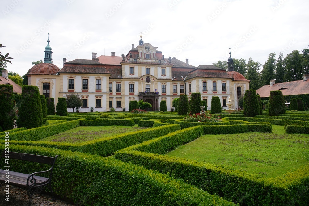Fototapeta premium Baroque chateau with manicured gardens under a cloudy sky.