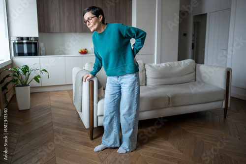 Tableau sur toile Senior woman clutching sofa in pain due to back injury