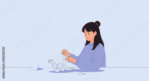 Young woman concentrating on creating an origami crane at the table indoors