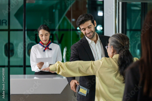 Foto Airline ground staff using metal scanner for security check every passenger in t