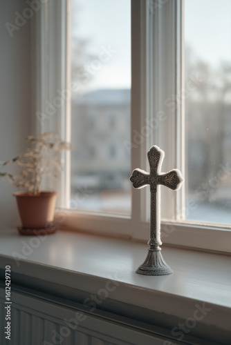 silver cross resting on frosty windowsill illuminated by ultrabright rays of sunlight