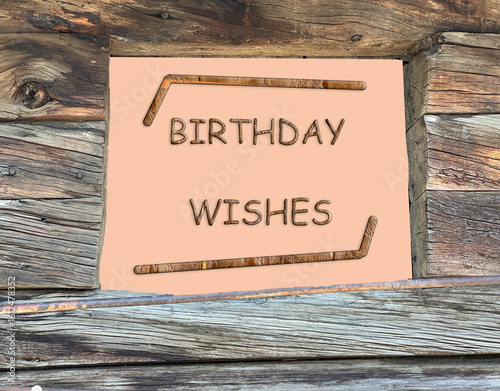 Birthday wishes with hockey sticks and old wood log cabin as the background. Letters are etched in wood. Words are underlined.