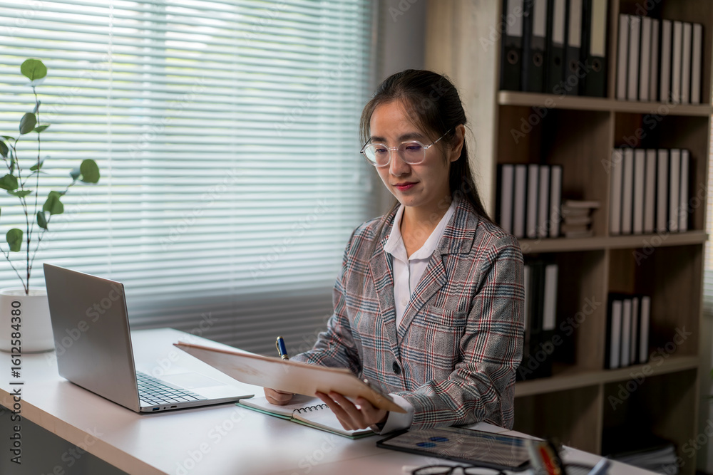 Fototapeta premium woman is sitting at a desk with a laptop and a notebook