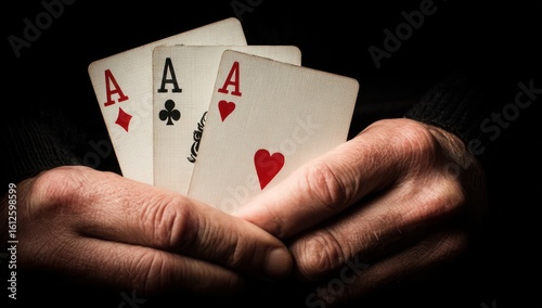 Hands holding three aces. One diamond, one club, one heart. Dark background emphasizing the cards. Close-up view reveals texture and detail