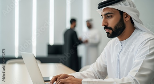 A businessman in traditional Middle Eastern attire works diligently on his laptop, showcasing professionalism and modern technology in a contemporary setting.