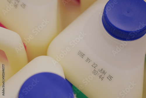 Fotografie Milk containers showing expiration dates in grocery setting