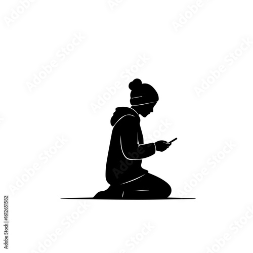 Silhouette of a person kneeling, looking at a phone, wearing winter clothing.