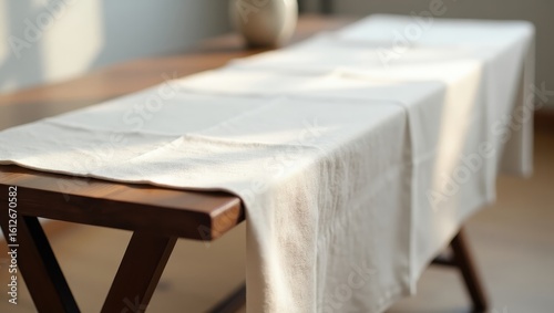 Light beige linen table runner on a wooden table.