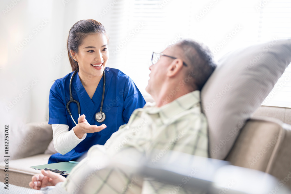 Fototapeta premium Young friendly asian female nurse or caregiver talking to elderly man in nursing home