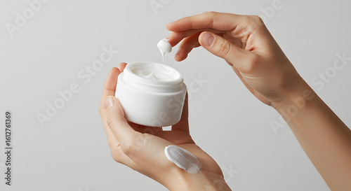 Hands of woman using jar of beauty cream