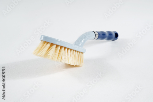 Hard bristle cleaning brush with long blue handle and ergonomic gray grip, isolated on white background