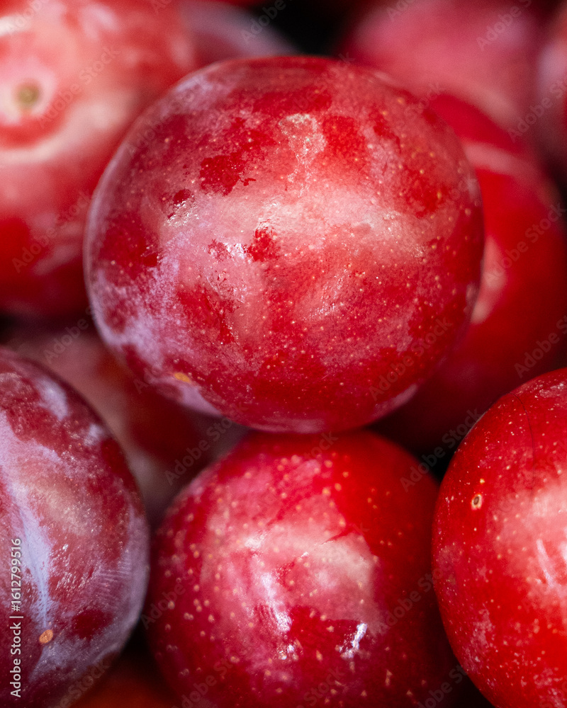 Obraz premium Close-up of fresh ripe red plums with natural bloom and rich texture. Ideal for food, harvest, and healthy lifestyle themes.