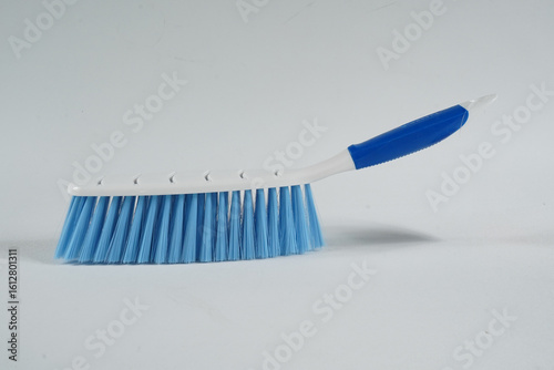 Hard bristle cleaning brush with long blue handle and ergonomic gray grip, isolated on white background