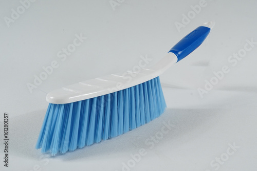 Hard bristle cleaning brush with long blue handle and ergonomic gray grip, isolated on white background