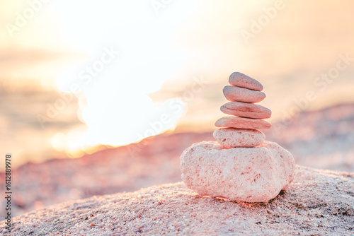 Canvas Print Stacked stones balanced on a beach at sunset, symbolizing peace and harmony in nature