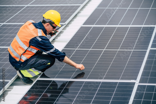 Worker inspects solar panels on a rooftop during daytime at a construction site