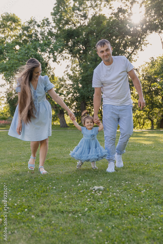 Fototapeta premium First steps. Baby learning to walk, with help of mothers and fathers hands.